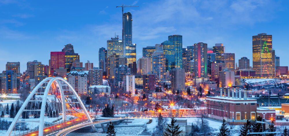Edmonton downtown Winter skyline just after sunset at the blue hour showing Walterdale Bridge across the frozen, snow-covered Saskatchewan River and surrounding skyscrapers. Edmonton is the capital of Alberta, Canada.