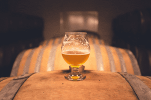Glass of beer sitting atop brewers barrel